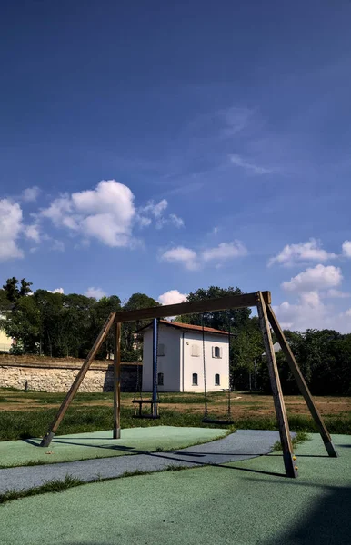 背後に白い建物のある公園で空のスイング — ストック写真