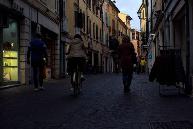 Dükkanları ve insanların gün batımında gezindiği bir İtalyan kasabası.