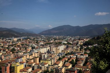 Gökyüzünden görünen şehir, güneşli bir günde ağaçlar ve çatılarla çevrili.