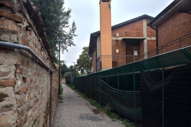 Çit ve tuğla duvarla çevrili çakıl yolu.