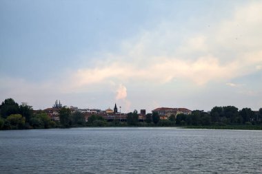 Göl kıyısında bir kasaba. Bulutlu bir günde. Uzaktan görülüyor.