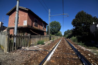 Gün batımında yanında ağaçlar ve binalar olan demiryolu geçidi
