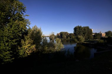 Gün batımında göl ağaçlarla çevrili ve kıyıdan görülüyor.