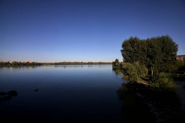 Göl kıyısında ağaçlar, gün batımında gökyüzünden görülüyor.
