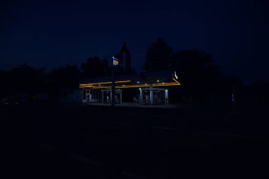 Akşam karanlığında IP ile işaretlenmiş bir benzin istasyonu.