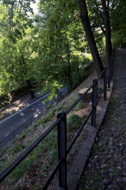 Bir tepedeki yol, bir parkın üstündeki patikadan görünüyor.