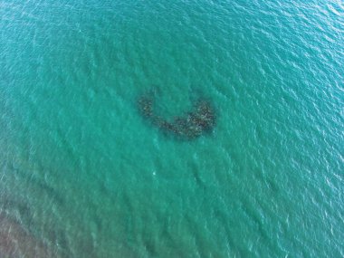 Denizde ay şeklinde kayalık bir adanın havadan görünüşü