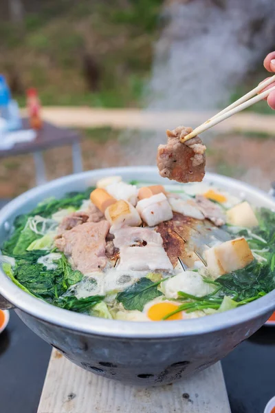 Yakın plan yemek çubuklarını tutarak tavadan ızgara domuz eti, Tayland usulü barbekü.