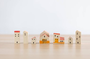Beyaz arka planlı ahşap masaya dizilmiş sevimli ev modelleri