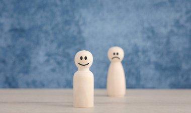 focus on happy faces wooden doll with blue background for satisfaction survey, mental health assessment
