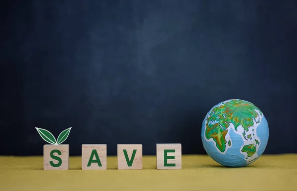 wood cube block with SAVE word and globe model on dark blue background, environment preservation concept