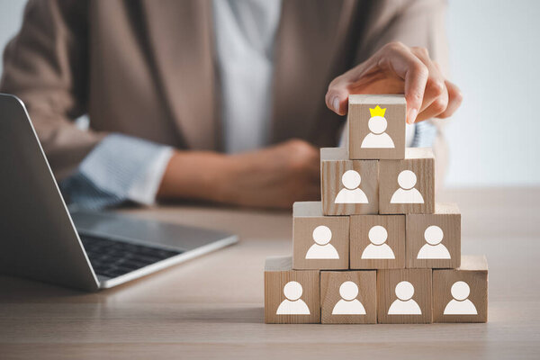 business woman hand holding top wood cube block with man on crown icon, human resource management concept