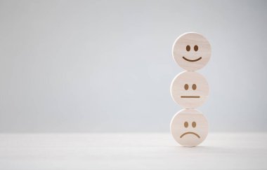 Tatmin olmak için çeşitli duygu yüzleri olan yuvarlak tahta yığını, zihinsel sağlık değerlendirmesi.