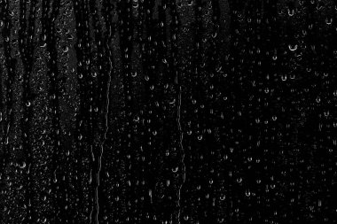 Temiz camın yüzeyinden aşağı siyah bir zemin üzerinde su damlaları akar. Yaratıcılık için doku.