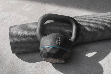 Kettlebell ve yoga minderi evde yerde. spor aletleri.