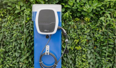 Otoparktaki elektrikli araba şarj istasyonu EV bataryası için. Yeşil güç ve gelecekteki ulaşım teknolojisi kavramı.