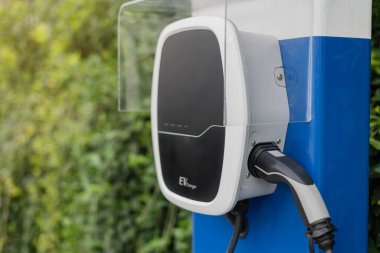 Otoparktaki elektrikli araba şarj istasyonu EV bataryası için. Yeşil güç ve gelecekteki ulaşım teknolojisi kavramı.