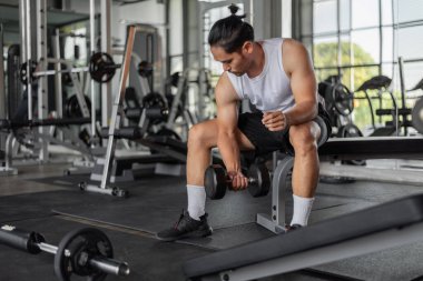 Asyalı adam spor yapıyor. Spor elbiseli genç bir adam spor salonunda silah egzersizi yapıyor..