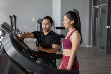 Spor salonunda kişisel antrenörle Asyalı kadın egzersizi. Genç sağlıklı bir kadın antrenörle spor yapıyor..