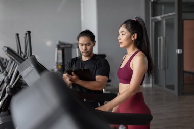 Spor salonunda kişisel antrenörle Asyalı kadın egzersizi. Genç sağlıklı bir kadın antrenörle spor yapıyor..