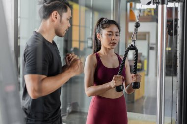 Spor salonunda kişisel antrenörle Asyalı kadın egzersizi. Genç sağlıklı bir kadın antrenörle spor yapıyor..