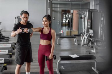 Spor salonunda kişisel antrenörle Asyalı kadın egzersizi. Genç, sağlıklı bir kadın kişisel koçla spor yapıyor..