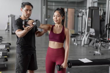 Spor salonunda kişisel antrenörle Asyalı kadın egzersizi. Genç, sağlıklı bir kadın kişisel koçla spor yapıyor..