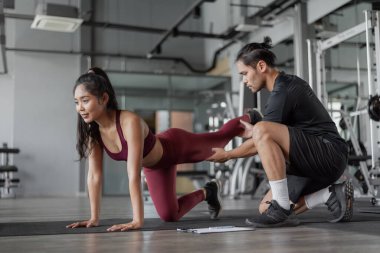 Spor salonunda kişisel antrenörle Asyalı kadın egzersizi. Genç, sağlıklı bir kadın spor salonunda antrenman yapıyor..