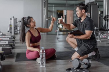 Spor salonunda kişisel antrenörle Asyalı kadın egzersizi. Sağlıklı kadın bana kişisel antrenörle beş dakika ver..