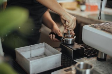 Barista, portafilter 'a kahve basmak için kurcalayıcı kullanıyor. Kahve makinesiyle kahve yapmak için ellere yakından bakın. Kahve sahibi konsepti.
