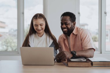Beyaz kız ailesiyle birlikte online ders alıyormuş. Küçük tatlı kız dizüstü bilgisayarını kullanarak babasıyla birlikte evde oturup bilgisayar eğitimi alıyor. Eğitim ve E-öğrenme kavramı.