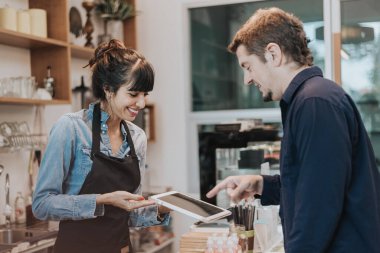 Kafkasyalı kadın kahveci, kahve dükkanındaki müşterilerden sipariş alır. Bayan barista sipariş almak için dijital tablet kullanıyor. Kahve sahibi konsepti.