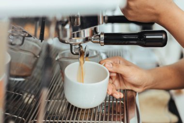 Barista kahve makinesiyle kahve yapıyor. Makineyle espresso yapmaya ellerinizi yakın tutun. Kahve sahibi konsepti.