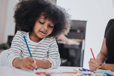 Afrikalı küçük çocuk annesiyle resim yapmayı öğreniyor. Afrikalı çocuklar evde gülümsüyor ve resim çiziyor..
