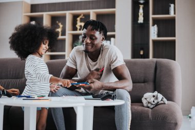 Mutlu aile evde eğleniyor. Küçük kızları olan Afrikalı bir baba evde birlikte oynuyor. Mutlu aile zamanları..