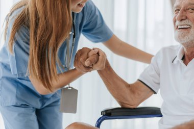 Hemşireden kıdemli adama yardım ve destek. Genç hemşire ve yaşlı adam destek olmak için el ele tutuşuyorlar. Yardım eden eller, yaşlı kavramına dikkat edin..