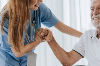 Hemşireden kıdemli adama yardım ve destek. Genç hemşire ve yaşlı adam destek olmak için el ele tutuşuyorlar. Yardım eden eller, yaşlı kavramına dikkat edin..