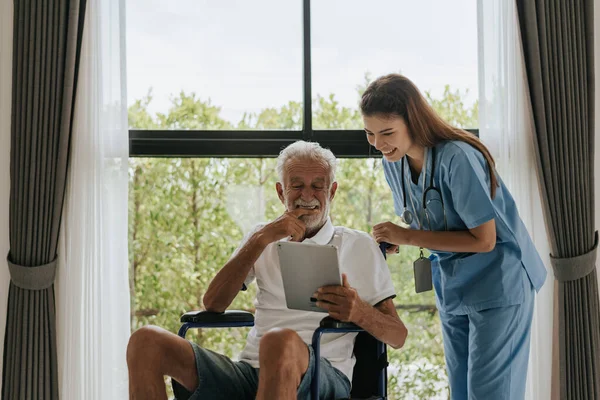 Asian nurse and senior man looking medical record on digital tablet at home. Old man and nurse using digital tablet together to looking health plan. Senior care