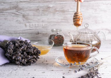 Şeffaf, kokulu bal, lavanta çaylı cam bir fincana dökülür.