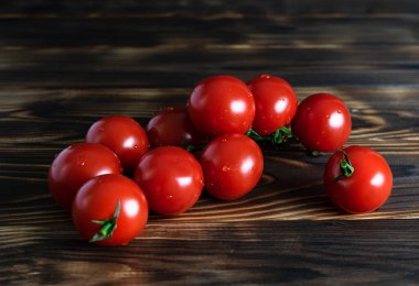 Yeşil bir dal üzerinde sulu kırmızı vişneli domatesler.