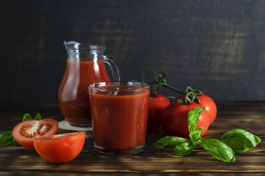 Koyu ahşap bir masada berrak bir bardakta domates suyu.