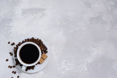 Beyaz seramik bardakta, çimento altında, beyaz gri bir zeminde, siyah, taze demlenmiş kahve.