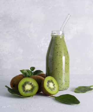 Taze kivi ve ıspanaklı smoothie şeffaf bir şişe içinde ve ışık masasında cam bir tüp ile