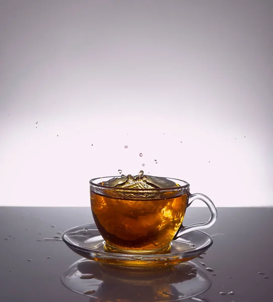 Kawałki Herbaty Lecą Przezroczystego Szklanego Kubka Lekkie Tło Lustra Lekka — Zdjęcie stockowe
