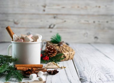 Beyaz bardaktaki sıcak, kokulu kakao, üzerinde tarçın çubukları olan ahşap bir masa.