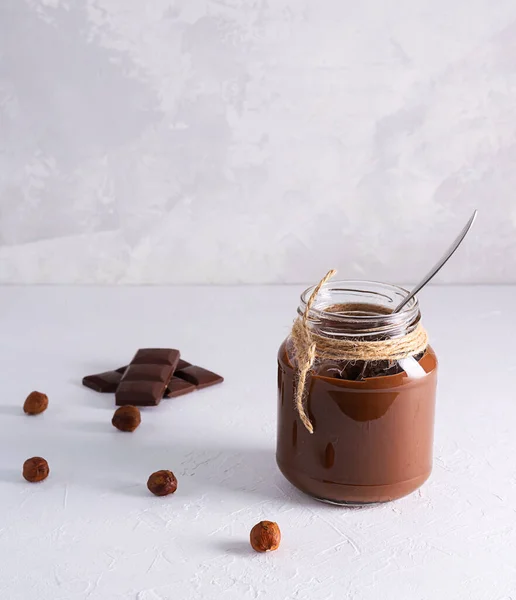 Chocolate-nut paste in a transparent glass jar on a light table