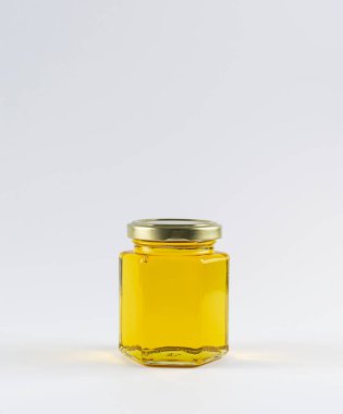 A glass jar with honey on a white background. Transparent golden nectar. Isolate on a white background. There is a place for text at the top