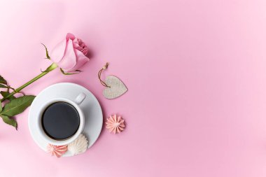 A white cup with fragrant black coffee on a pink background