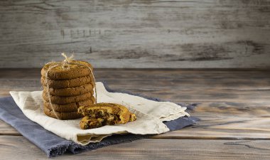 Yulaf ezmeli kurabiyeler hafif bir peçeteye bağlanmış bez parçasıyla. Açık kahverengi ahşap arka planda gri peçete. Metin için boşluk