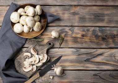 Koyu kahverengi tahta üzerinde dilimlenmiş şampiyonlar. Masanın üzerinde gri bir peçete var. Üst görünüm, metin için boşluk